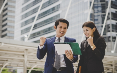 Dua orang sedang tersenyum dan melihat dokumen