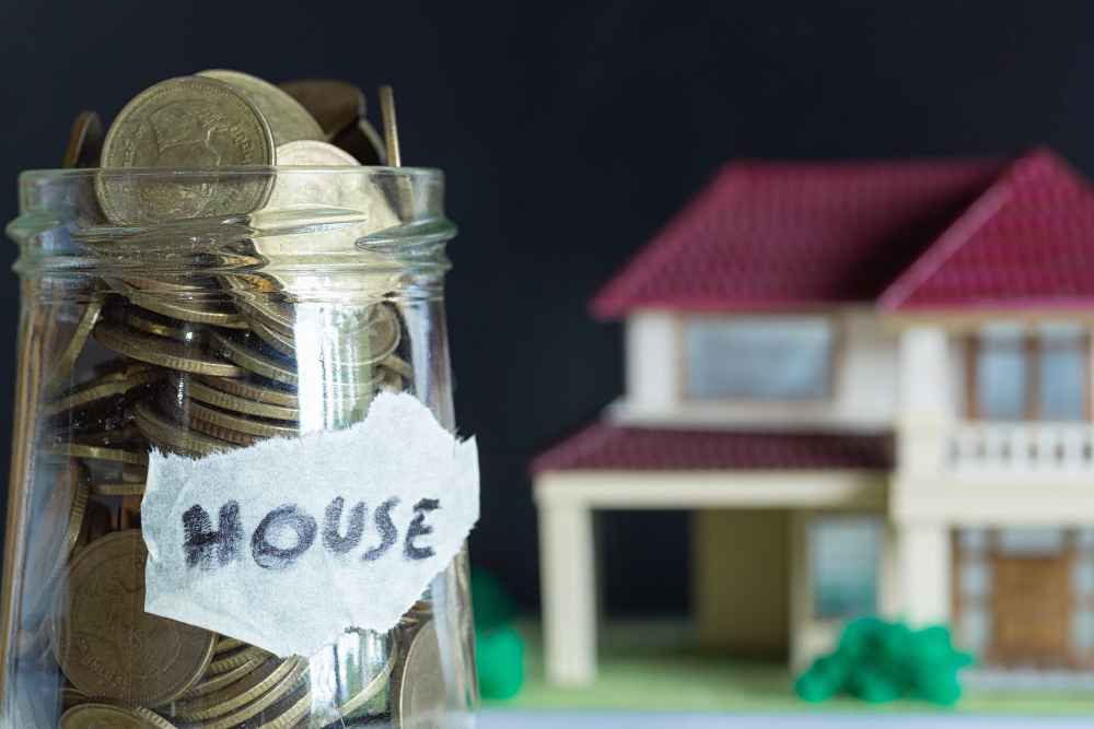 Uang koin dalam toples dan miniatur rumah
