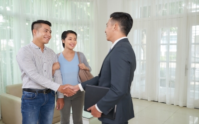 Agen properti sedang berjabat tangan dengan klien di dalam rumah