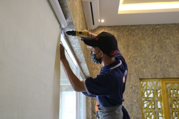 Orang sedang memperbaiki jendela rumah.